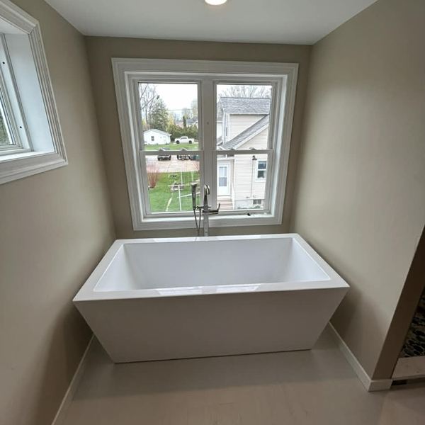 Freestanding soaking tub installed under a window by KW Plumbing